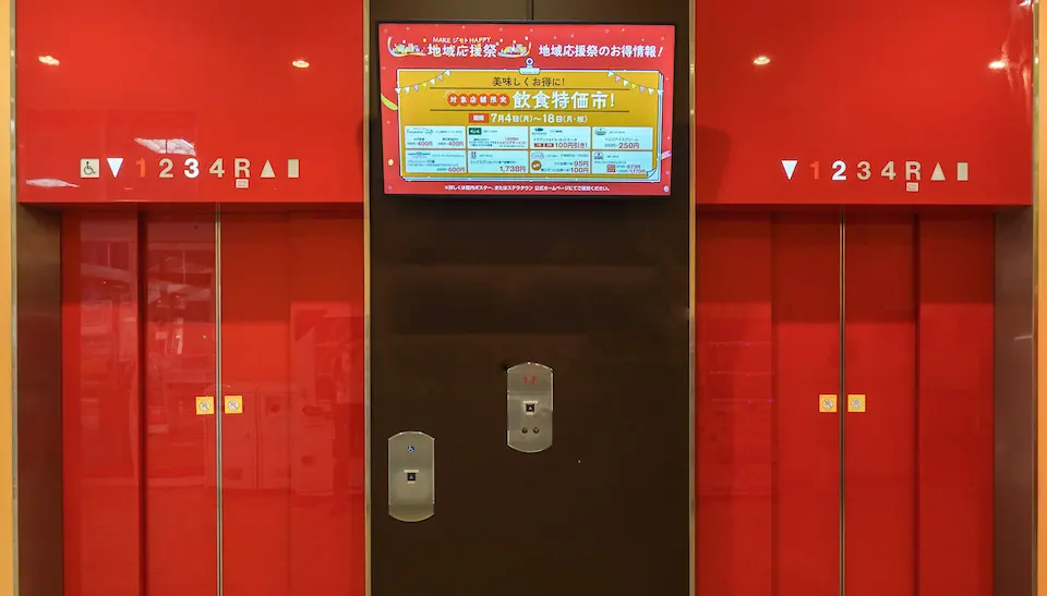 2機のエレベーターの間に設置されたデジタルサイネージ